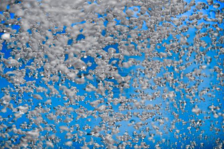 Photo for A stream of shiny air bubbles illuminated by light and shining on a blue background. Close up of light lit oxygen bubbles flow upwards. Aeration or filtration of liquid. Fizzy flow of air bubbles - Royalty Free Image