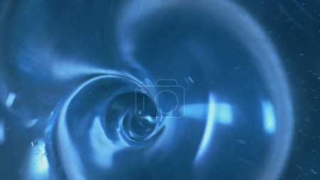 Photo for The surface of clear blue water swirls into a whirlpool and a funnel is formed. Swirl of a transparent liquid. Draining water, leaking in the bathroom or sink. A round hole from a water vortex is - Royalty Free Image