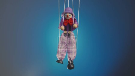 Téléchargez les photos : Marionnette clown accroché à des cordes. Une poupée en chiffon dans un costume violet et un chapeau, avec un arc rouge, le nez et le maquillage. Funster arlequin poupée douce sur fond bleu studio. Le concept de vacances pour enfants - en image libre de droit