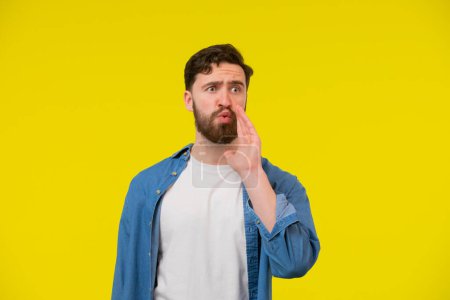 Photo for Shouting young man with his mouth wide open. Male model in a blue shirt on a yellow background. Emotions, advertisement concept. - Royalty Free Image
