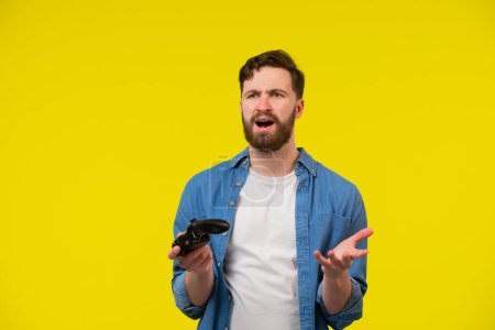 Photo for Close up photo of nervous scary fan of video games, he is holding a console, isolated on bright yellow background, copyspace - Royalty Free Image