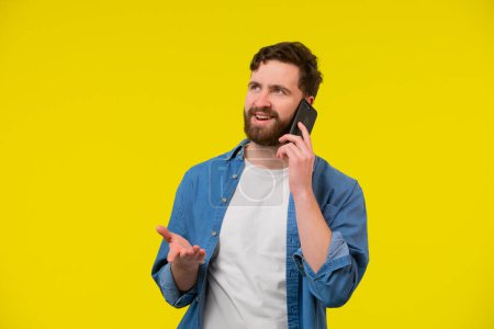 Photo for Young smiling happy cheerful caucasian man 20s wear white casual shirt talk speak on mobile cell phone conducting pleasant conversation look aside isolated on plain yellow background studio portrait. - Royalty Free Image