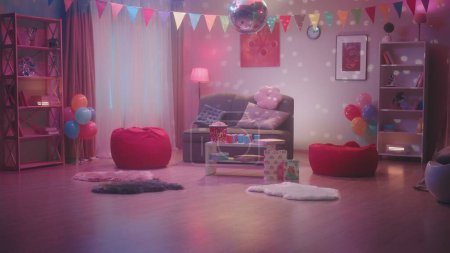 Foto de La habitación está decorada para las vacaciones con banderas, globos. La bola disco espejada cautiva con su resplandor colorido y reflejos multicolores. Una mesa con palomitas de maíz, pizza y vasos de papel - Imagen libre de derechos