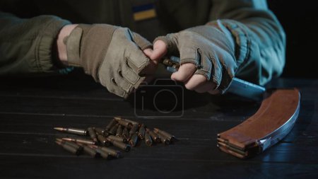 Foto de Las manos masculinas de un militar ucraniano cargan un cargador de rifle de asalto kalashnikov con cartuchos de cerca. Guerra en Ucrania. Agresión rusa e invasión militar de Ucrania - Imagen libre de derechos