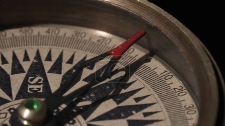 Photo for Vintage compass close up on a black background. The red tipped compass arrow points south. The concept of travel, adventure, expeditions, business, choice and opportunity - Royalty Free Image