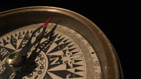 Photo for Travel planning navigation concept. Vintage magnetic compass with a a rotating arrow close up on a black background - Royalty Free Image