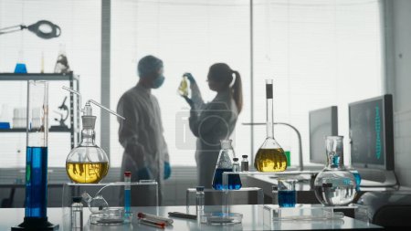 Photo for Modern medical research laboratory. Two scientists working together analyze a plant sample in an Erlenmeyer flask, discuss the result. Blurred background. Advanced scientific lab for medicine - Royalty Free Image