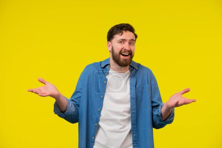 Photo for A portrait of a bearded man with open palms and confused face expression. Looking clueless, having no idea. Eyes and mouth wide open. Isolated on yellow background. - Royalty Free Image