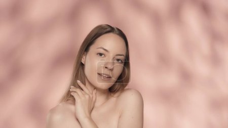 Photo for A young woman enjoys her perfect smooth, delicate skin. Portrait of a smiling seminude woman, isolated on a pink background close up. The concept of beauty, cosmetology, skin care, spa - Royalty Free Image
