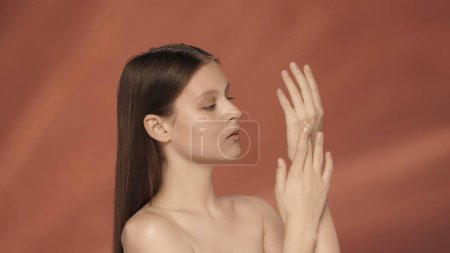 Photo for Hand care and protection. A young woman enjoys the smoothness and softness of the skin on her hands. Seminude woman in the studio on a red background. The concept of beauty, cosmetology, care - Royalty Free Image