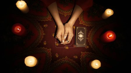 Photo for Fortune teller session scene. Close up shot of female hands on the table with a deck of tarot cards laying next to her. Preparation for divination. Esoteric concept. - Royalty Free Image
