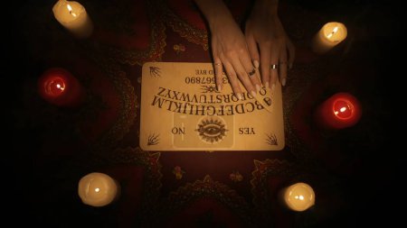 Photo for Magical session scene, top view. Close up shot female model hands moving over spiritual board and trying to read the message from ghosts, using ouija game. Occult divination concept. - Royalty Free Image