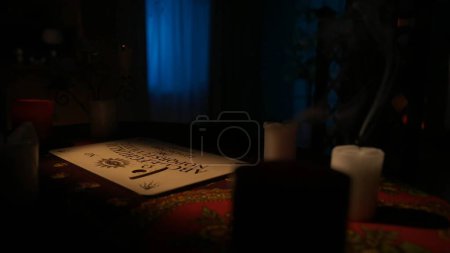 Photo for Magical session scene. Close up shot of spiritual board game with alphabet and numbers laying on the table, many blown out candles standing around. Occult divination concept. - Royalty Free Image