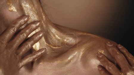 Photo for Close up shot of a female model shoulder and collarbone area. Woman applying the golden liquid paint over her body skin. Beauty advertisement concept. - Royalty Free Image