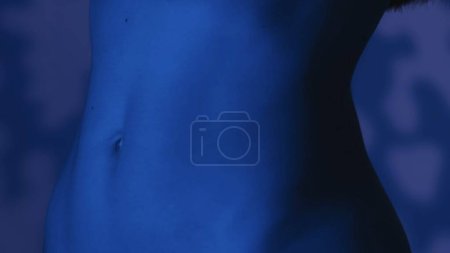 Foto de Mujeres delgadas en la cintura a vista de cerca. Esquema de color azul, atmósfera nocturna, fondo cubierto de sombras suaves. Cosméticos u otros productos publicitarios. - Imagen libre de derechos