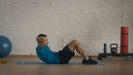 Photo for Closeup shot. Athletic fitness coach doing exercises at the home studio for online classes. Man doing classic abs crunches exercise. - Royalty Free Image