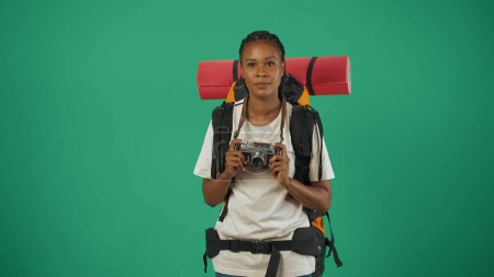 Téléchargez les photos : Portrait d'une touriste en tenue décontractée avec sac à dos. Voyager en temps libre concept. Isolé sur fond vert. - en image libre de droit