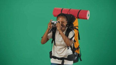 Photo for Portrait of a female tourist in casual clothes with backpack. Travelling in spare time concept. Isolated on green background. - Royalty Free Image