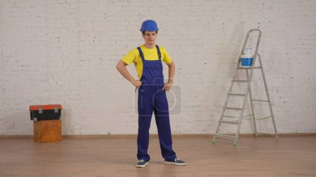 Photo for Full length shot of a young construction foreman standing in the room under renovation with his hands on his hips, looking at the camera. Repairing, company advertisement. - Royalty Free Image