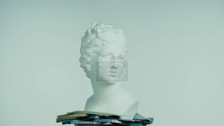 Photo for Closeup shot of beautiful ancient goddess Venus marble statue with money around her. Portrait of roman era female bust on a platform. Isolated on blue background. Creative abstract concept. - Royalty Free Image