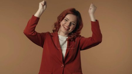Photo for Medium isolated shot of a satisfied, happy and active young woman shaking her fists in sign of success and win. Woman is smiling at the camera. Business content or advertisement. - Royalty Free Image