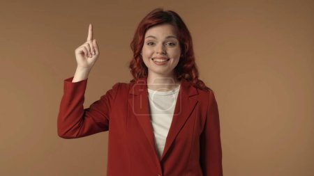Photo for Medium isolated shot of a young woman happily pointing her finger in the air as if she came up with an idea. Creative business content or advertisement. - Royalty Free Image