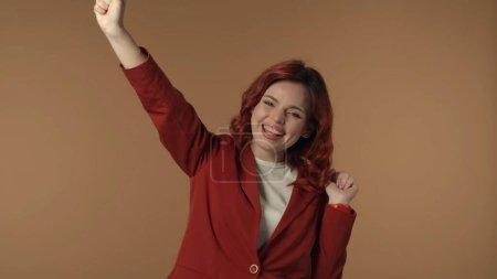 Photo for Medium isolated shot of a satisfied, happy and active young woman shaking her fists in sign of success and win. Woman is smiling at the camera. Business content or advertisement. - Royalty Free Image