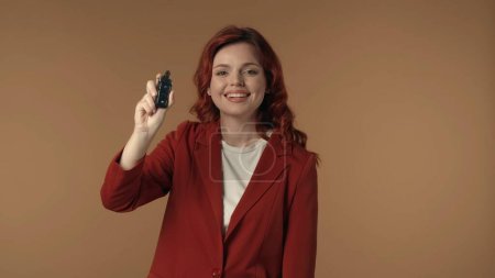Photo for Medium isolated shot of an astonished, happy and active young woman holding a car key in her hand and expressing pure joy about the purchase. Car seller, distributer, online resource advertisement. - Royalty Free Image