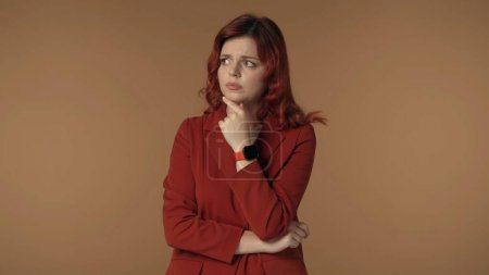 Photo for Medium isolated shot of a young woman pensively looking away as if shes trying to come up with an idea or doubting some decision, while touching her chin. Creative content or advertising. - Royalty Free Image