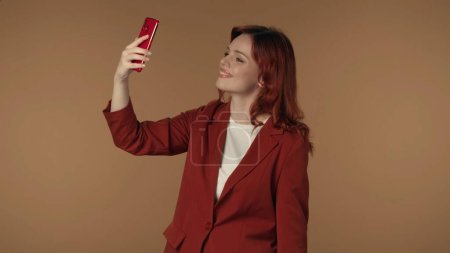 Photo for Medium isolated shot of a young woman holding a smartphone in her hand, making a video, live or a photo for her social media. Internet, posting, online content and app advertisement. - Royalty Free Image