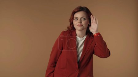 Photo for Medium isolated shot of a joyful young woman looking to the sides and raising hand up to her ear to listen to the secrets and rumors. Creative content, advertisement. - Royalty Free Image