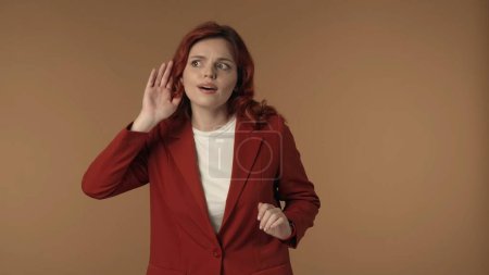 Photo for Medium isolated shot of a joyful young woman looking to the sides and raising hand up to her ear to listen to the secrets and rumors. Creative content, advertisement. - Royalty Free Image