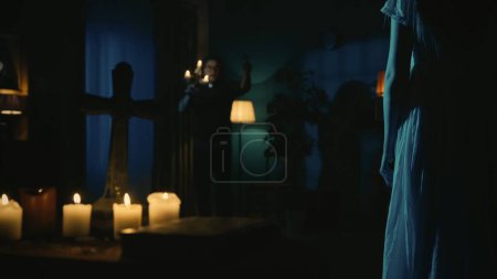 Téléchargez les photos : Abattu d'un prêtre s'approchant d'une femme possédée, fantôme, entité. L'exorciste tient une croix à la main, effrayant la créature paranormale. Contenu créatif, thème Halloween. - en image libre de droit