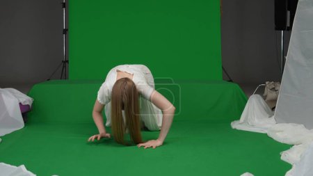 Photo for Full-size green screen shot of a posessed female, woman figure, ghost, poltergeist, zombie crawling towards the camera, hunched. The ring reference. Horror clip, advertisement, walking dead. Chroma - Royalty Free Image