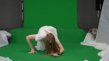 Photo for Full-size green screen shot of a posessed female, woman figure, ghost, poltergeist, zombie crawling towards the camera, hunched. The ring reference. Horror clip, advertisement, walking dead. Chroma - Royalty Free Image