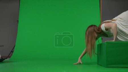 Photo for Full-size side view green screen chroma key shot of a posessed female, woman figure, ghost, poltergeist, zombie crawling over an obstacle. The ring reference. Horror clip, advertisement, walking dead - Royalty Free Image