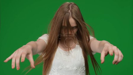 Photo for Medium green screen, chroma key shot of a posessed female, woman figure, ghost, poltergeist, zombie pulling her hands out to the camera. Hair is covering her face. Horror clip, advertisement, dead - Royalty Free Image