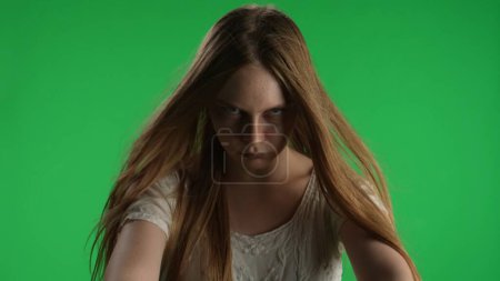 Photo for Medium green screen, chroma key shot of a posessed female, woman figure, ghost, poltergeist, zombie pulling her hands out to the camera. The wind blows her hair. Horror clip, advertisement, dead - Royalty Free Image