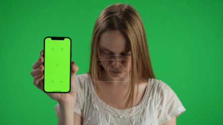 Photo for Medium green screen, chroma key shot of a posessed female, woman figure, ghost, poltergeist, zombie holding a smartphone with a mock up, banner, place for the advertisement. Horror clip, walking dead - Royalty Free Image