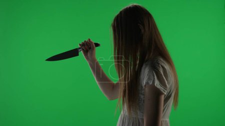 Photo for Medium side view green screen, chroma key shot of a posessed female figure, ghost, poltergeist, zombie raising, pulling out a knife, stabbing the air. Horror clip, advertisement, walking dead. Chroma - Royalty Free Image