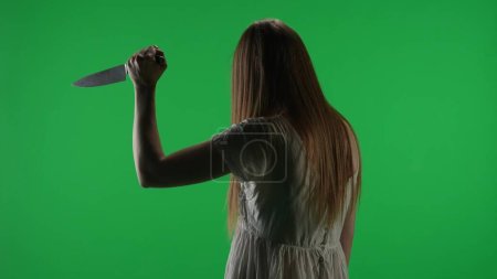 Photo for Medium half turn green screen, chroma key shot of a posessed female figure, ghost, poltergeist, zombie raising, pulling out a knife, stabbing the air. Horror clip, advertisement, walking dead. Chroma - Royalty Free Image