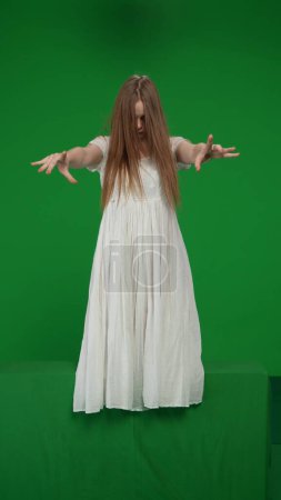 Photo for Full-size vertical green screen, chroma key shot of a posessed female, woman figure, ghost, poltergeist, zombie pulling her hands out to the camera. Horror clip, advertisement, walking dead. - Royalty Free Image