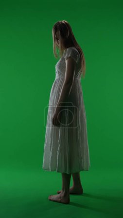 Photo for Full-size half turn vertical green screen, chroma key shot of a posessed female, woman figure, ghost, poltergeist, zombie turning her face to the camera. Horror clip, advertisement, walking dead. - Royalty Free Image