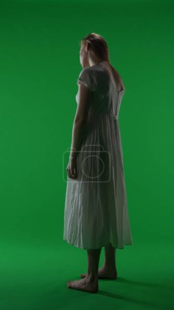 Photo for Full-size vertical green screen, chroma key shot of a posessed female, woman figure, ghost, poltergeist, zombie shot from behind. Shadowed figure. Horror clip, advertisement, dead. - Royalty Free Image