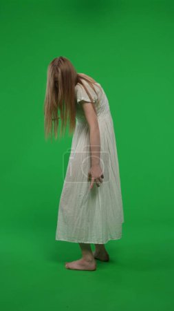 Photo for Full-size half turn vertical green screen, chroma key shot of a posessed female, woman figure, ghost, poltergeist, zombie turning her face to the camera. Horror clip, advertisement, walking dead. - Royalty Free Image