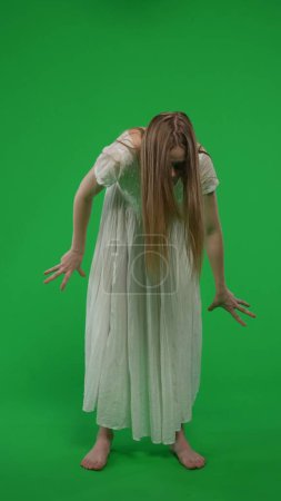 Photo for Full-size vertical green screen, chroma key shot of a posessed female, woman figure, ghost, poltergeist, zombie moving in an abrupt, convulsive manner. Horror clip, advertisement, walking dead. - Royalty Free Image