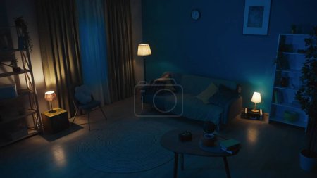 Photo for Picture of a flat, an apartment in the night. Muffled, low light, cozy room. Couch, sofa, table and other furniture in the room. Late night, after midnight. Creative content, advertisement. - Royalty Free Image