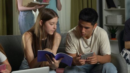 Photo for Medium shot of a boy and a girl sitting on a couch in a group of teens, young people, friends, studying, preparing for an exam, discussing, looking at their notes. Advertisement, school, university. - Royalty Free Image