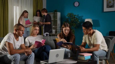Photo for Medium shot of a group of teens, young people, friends, studying, preparing for an exam, discussing, looking at their notes, using devices, watching something. Advertisement, school, university. - Royalty Free Image