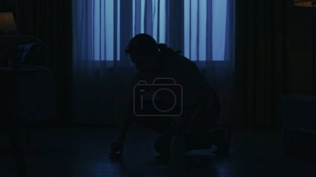 Photo for Portrait of female silhouette in the dark apartment room. Everyday life creative concept. Woman in casual clothing sitting, washing the floor with brush in the room. - Royalty Free Image